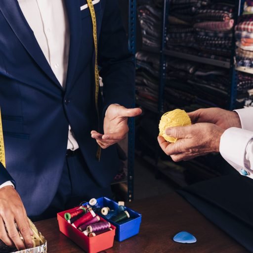 customer-s-hand-showing-yellow-wool-ball-male-fashion-designer-shop